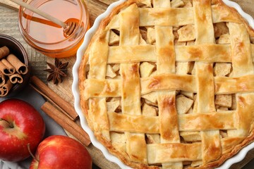 Delicious homemade pie, fresh apples, honey and cinnamon sticks on wooden table, flat lay