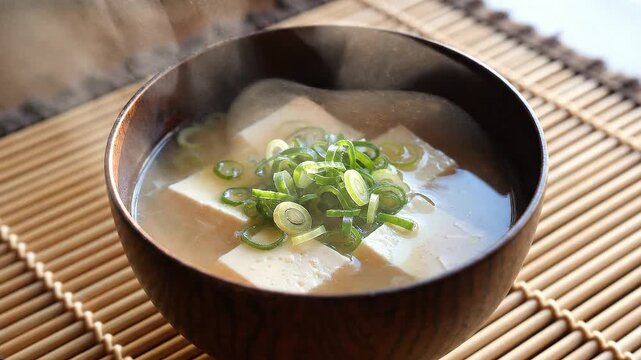 A warm and inviting bowl of traditional Japanese miso soup, garnished with fresh green onions and soft tofu