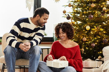 Joyful African American couple sharing holiday moments by the Christmas tree