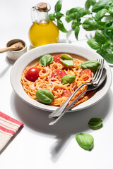 Delicious spaghetti with tomato sauce, cherry tomatoes, parmesan cheese and fresh basil on light background, Italian pasta dish top view