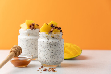 Mango chia pudding in glass jar and chocolate granola on orange minimalist background with copy space. Healthy breakfast concept