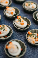 Homemade deviled eggs topped with golden croutons and fresh parsley, served in small green ceramic bowls. Bright, soft lighting with shallow depth of field for minimalist food styling.
