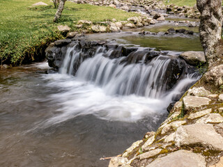 Soft waterfall in mountain botanical park with natural tones and calm atmosphere, great for travel visuals and eco lifestyle content
