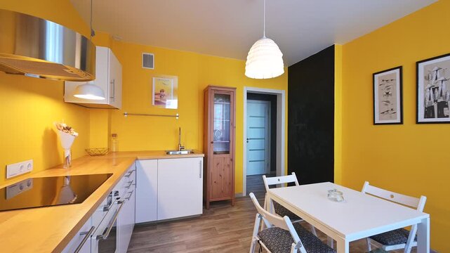 vibrant kitchen with yellow walls features white cabinetry, a wooden countertop, and a white table with chairs. Pendant lights illuminate the area. A mix of modern rustic decor