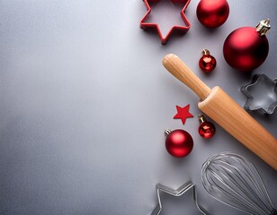 Top view of red glass christmas balls and various kitchen tools (rolling pin, whisk, spatula and cookie cutters) on gray background with copy sapce
