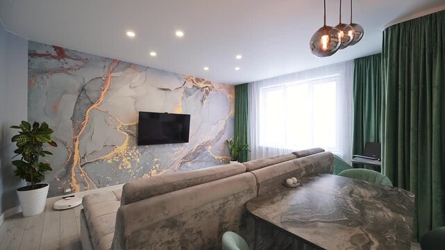 A stylish living room featuring a unique marble-patterned wall, a comfy couch, and a modern dining area with green chairs. A TV is mounted on the wall