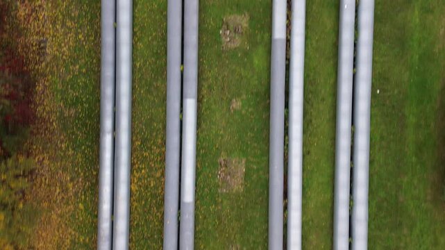 Aerial view of industrial pipes running across green landscape, showcasing gradual movement through foliage, highlighting the connection between heating and water systems, camera pans smoothly