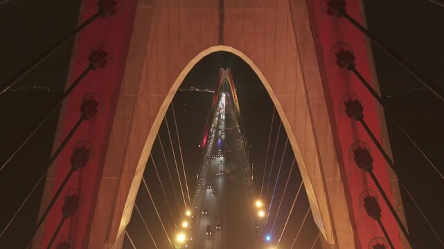 This 4K aerial night footage captures Cau Nhat Tan Bridge in Hanoi, Vietnam. The bridge glows with vibrant LED lights, reflecting beautifully on the Red River and revealing the dynamic energy of the c