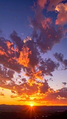Fototapeta premium Dramatic vertical view of a fiery orange and purple sunset sky over a distant landscape.