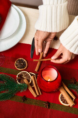 Setting a festive table with cinnamon sticks and warm candlelight for Christmas celebration