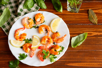 Hot shrimps with citrus slices and spices in a plate on a wooden