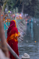  Chhath Puja, Portrait of unidentified hindu female devotee performing rituals of chhath with standing in river to worship lord sun during sunset.