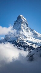 The majestic snow covered peak of the Matterhorn mountain surrounded by clouds.