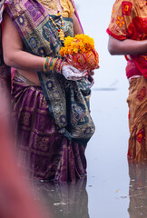  Chhath Puja, Portrait of unidentified hindu female devotee performing rituals of chhath with standing in river to worship lord sun during sunset.
