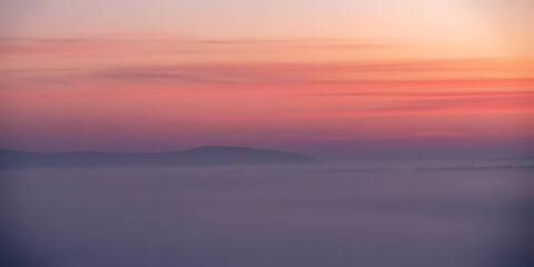 Fototapeta premium Soft gradient dawn sky with subtle pink and purple hues over a calm horizon
