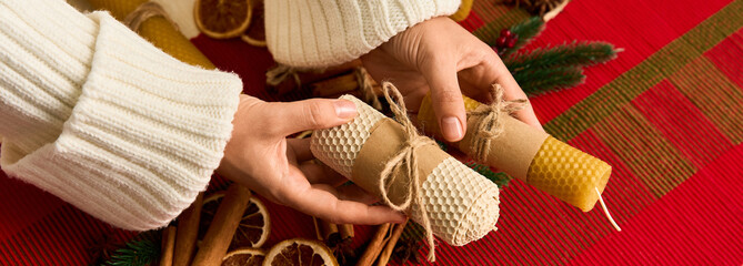 Hands preparing festive bee wax candles for a cozy Christmas celebration at home