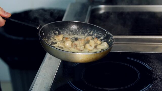 Person cooking creamy mushroom mixture in frying pan. Steam rising from pan on electric cooktop.