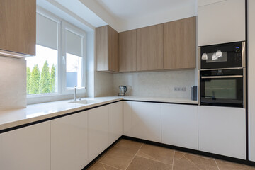 Modern and minimalist kitchen with white furniture, wooden elements.