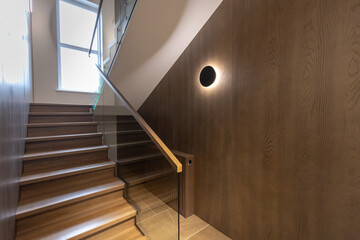Wooden staircase with glass railings and wooden handrail.