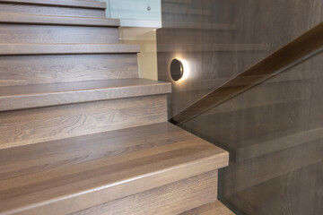 Wooden staircase with glass railings and wooden handrail.