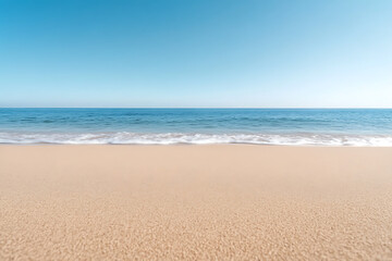Fototapeta premium A tranquil beach scene unfolds with soft, tan sand meeting gentle, azure waves under a clear blue sky. The horizon is a seamless blend of ocean and sky, inviting peace.