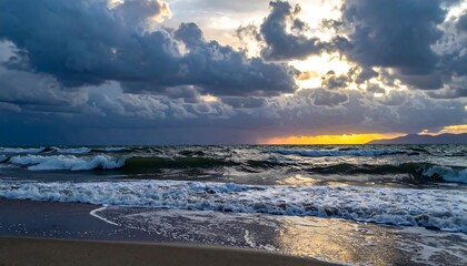 Dramatic seascape showcases turbulent ocean waves under a stormy, cloud-filled sky during a vibrant sunset. Golden sunlight bursts through breaks