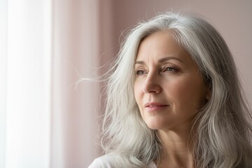 Naklejka premium Thoughtful mature woman with long grey hair looking away. Portrait of a pensive senior lady. Graceful aging and menopause concept