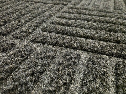 Close-up texture of gray doormat surface. Detailed macro view of a gray textured doormat with ribbed pattern, commonly used for wiping shoes at entrances