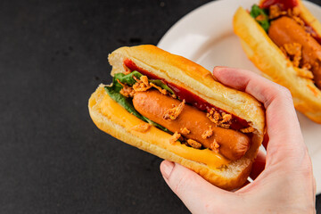 Hotdog fried onions, sausage, bun, sauce fast food tasty snack fresh delicious gourmet food background on the table rustic top view copy space