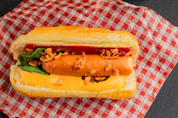 Hotdog fried onions, sausage, bun, sauce fast food tasty snack fresh delicious gourmet food background on the table rustic top view copy space