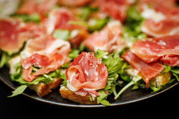 Prosciutto and arugula bruschetta on dark plate