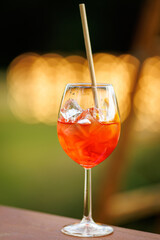 Glass of orange cocktail with ice outdoors