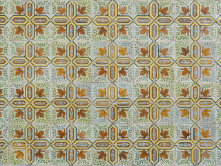 Detailed pattern of traditional Portuguese Azulejo tiles featuring ocher, brown, and green leaves and geometric shapes, Lisbon, Portugal.