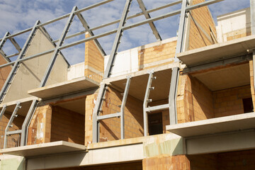 Temporary supports behind prefabricated panels, Bright evening sunlight highlights construction process