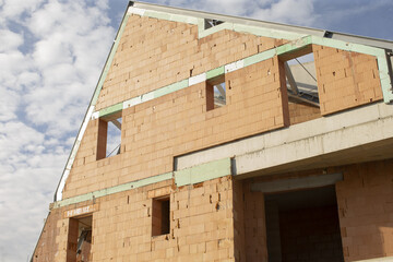 Incomplete masonry residence with roof, Unfinished brick home featuring gable roof and exposed walls