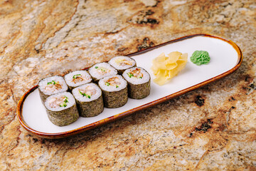 Delicious sushi rolls served on a white plate with condiments