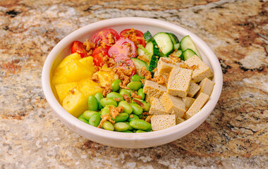 Colorful bowl of fresh vegetables and tofu on a marble surface