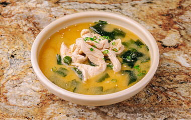 Warm chicken soup with seaweed on a natural stone surface