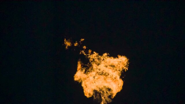 Rage of the Fire. A powerful pillar of bright flame with swirling fiery tongues in the air on a black background. Slow Motion