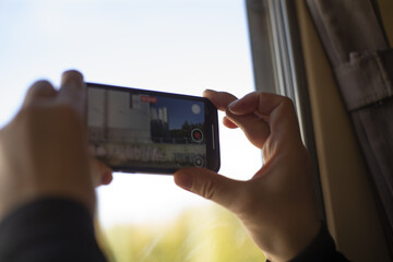 Urban filming scene, Content creator documents city skyline from apartment window using smartphone