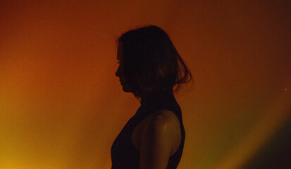 A moody, neon portrait of a woman's silhouette, showing her shoulders, with creative lighting and motion blur
