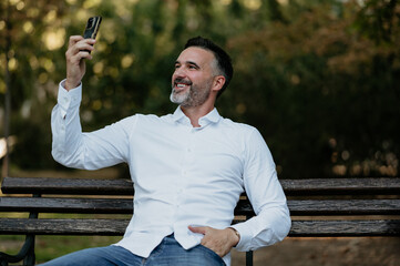 Man taking selfie outdoors on park bench