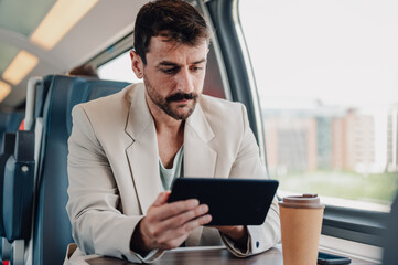 Businessman commuting on train checking digital tablet