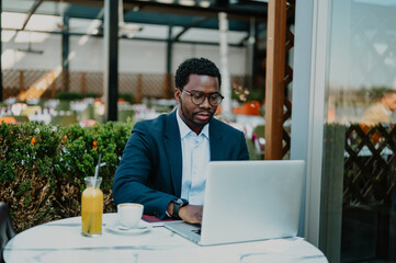 Black businessman working on laptop at outdoor cafe