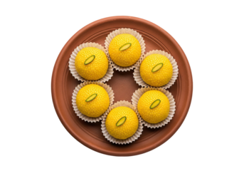 A circular arrangement of six golden yellow indian sweets garnished with pistachios on a brown plate isolated on transparent background