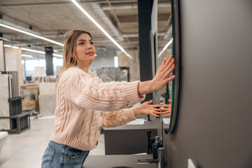 Smiling Woman Adjusting Circular Mirror in Modern Interior Store