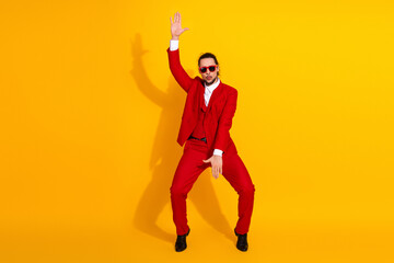 Funny stylish red suit man dances in bold outfit against bright yellow backdrop for fashion fun and modern energy