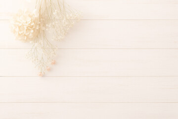 左上に配置されたドライフラワーの花束　白い木目の背景素材