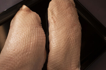 Two fresh, raw duck breast fillets are beautifully displayed on an elegant black tray, ready for cooking