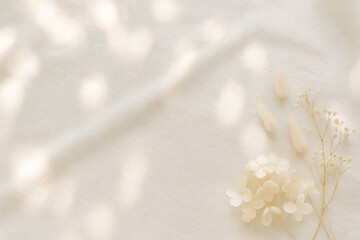 光が差し込む布地とかわいい小花のドライフラワーの背景素材　木漏れ日